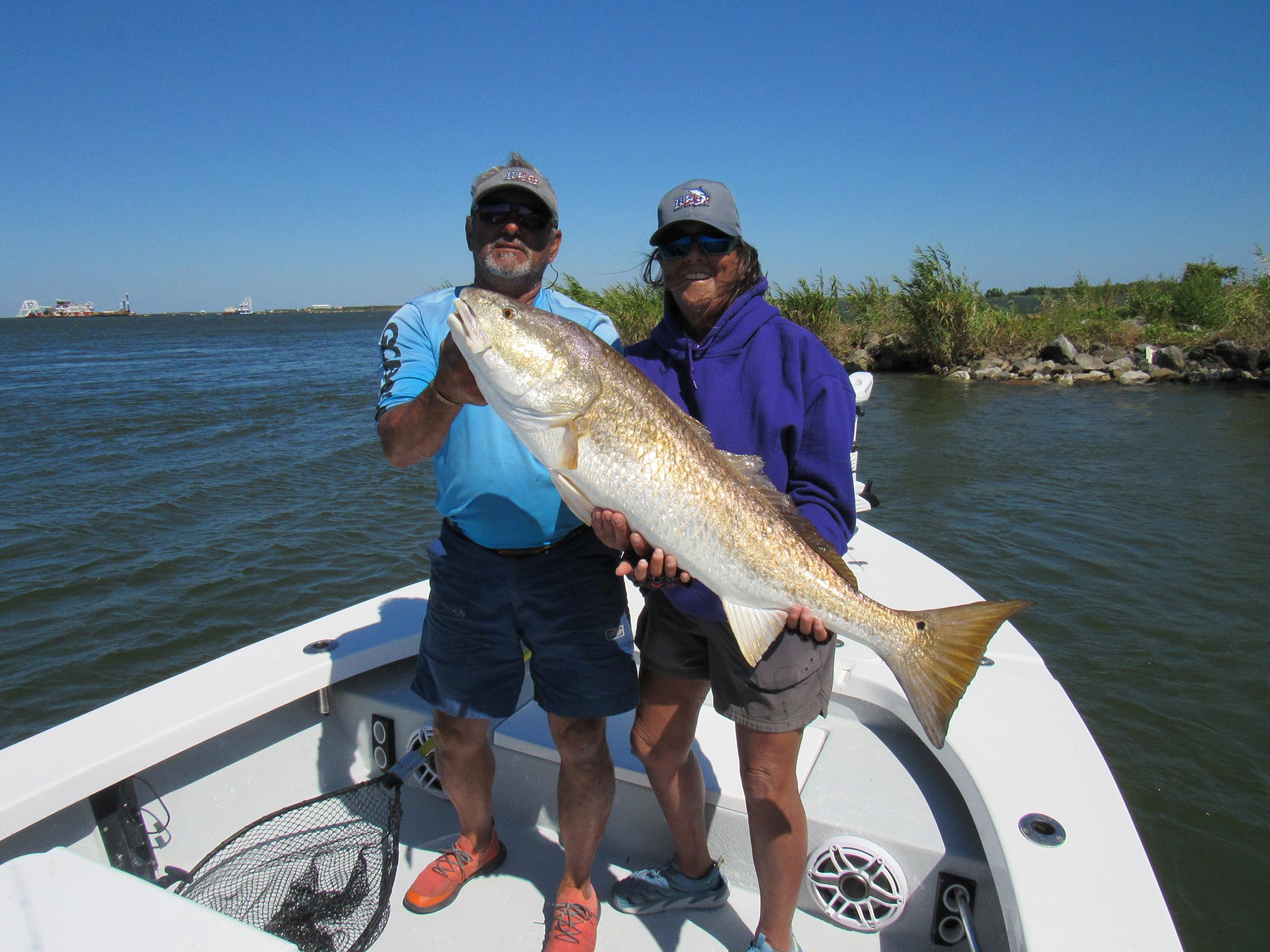 two veterans on boat from fishing trip with large fish