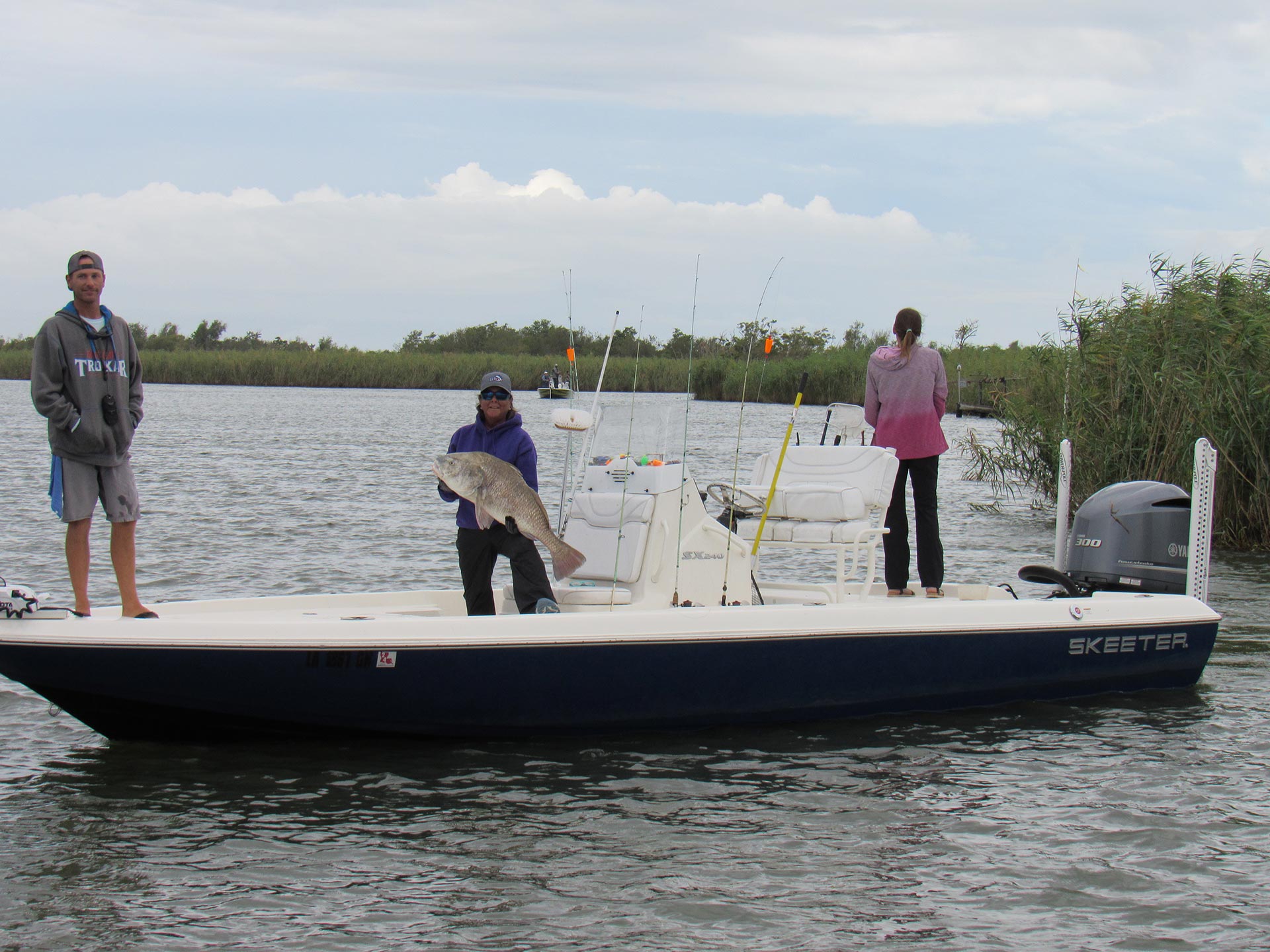 three veterans on boat from fishing trip with large fish