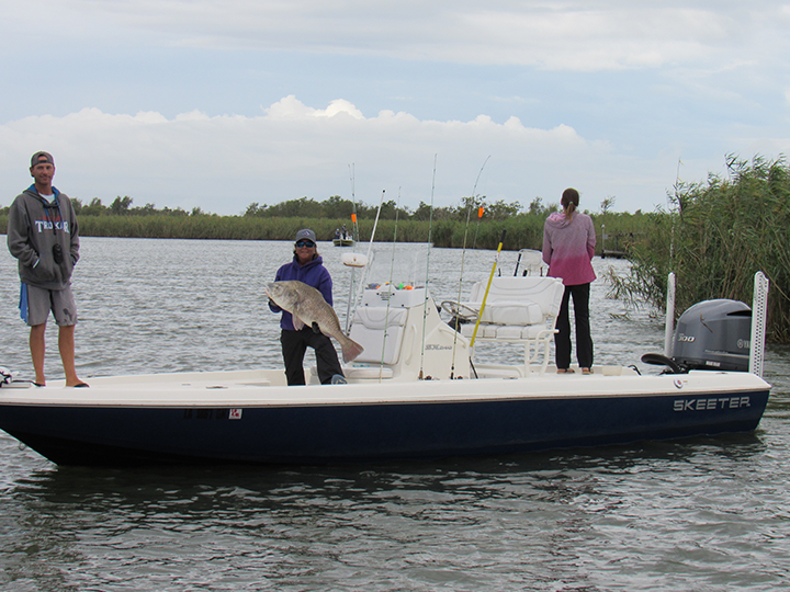 three veterans on boat from fishing trip with large fish